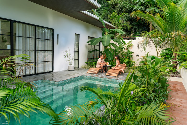 Pareja descansando en tumbonas junto a la piscina privada exclusiva